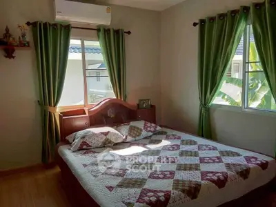 Cozy bedroom with quilted bedspread and green curtains, inviting natural light.