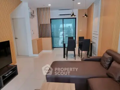Modern living room with sleek furniture and dining area, featuring a large window with city view.