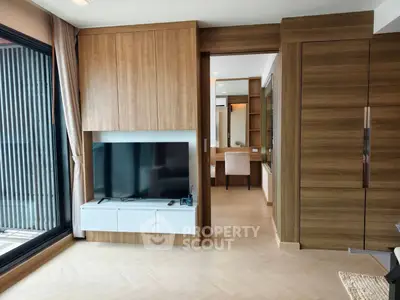 Modern living room with sleek wooden paneling and large TV, leading to a stylish study area.