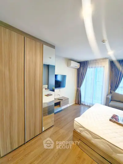 Modern bedroom with wooden flooring, mirrored wardrobe, and large window with curtains.