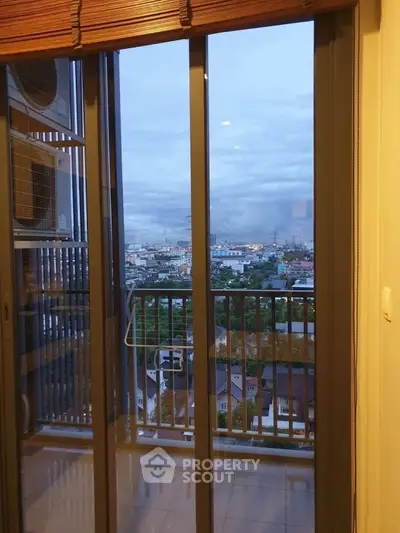 Stunning city view from modern apartment balcony with glass doors.