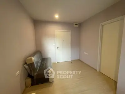 Minimalist room with wooden flooring and a covered sofa, perfect for a cozy living space.