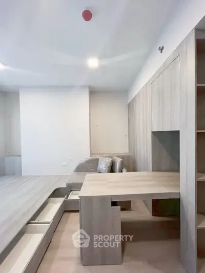 Modern minimalist living space with built-in wooden furniture and ample storage solutions.