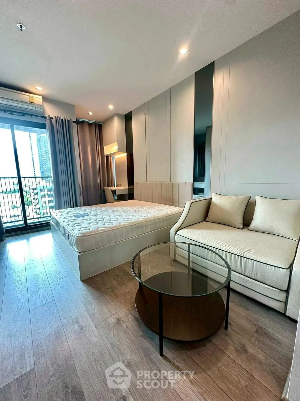 Modern bedroom with balcony view, featuring elegant furnishings and natural light.