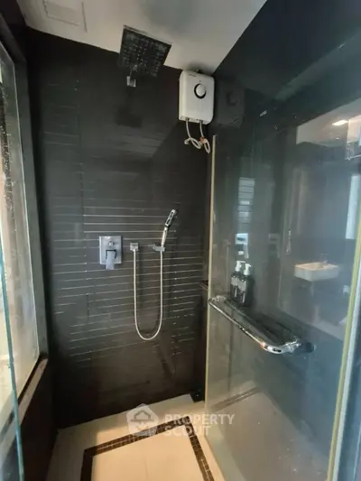 Luxurious modern bathroom with sleek black tiles and high-end shower fixtures.