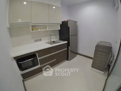 Modern kitchen with sleek cabinetry, stainless steel fridge, and built-in oven in a compact layout.