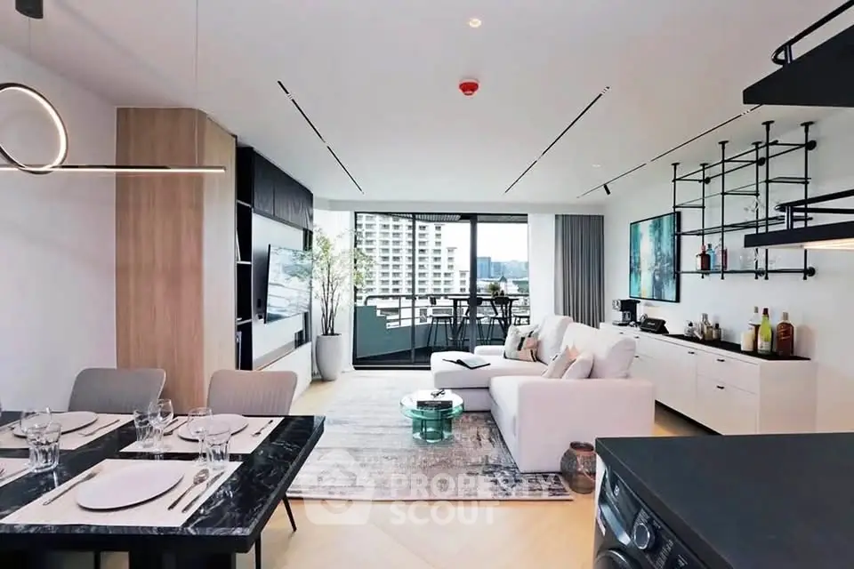 Modern open-plan living room with stylish decor and balcony view in a high-rise apartment.