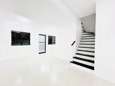 Spacious white interior with staircase and tiled floor, ideal for modern living.