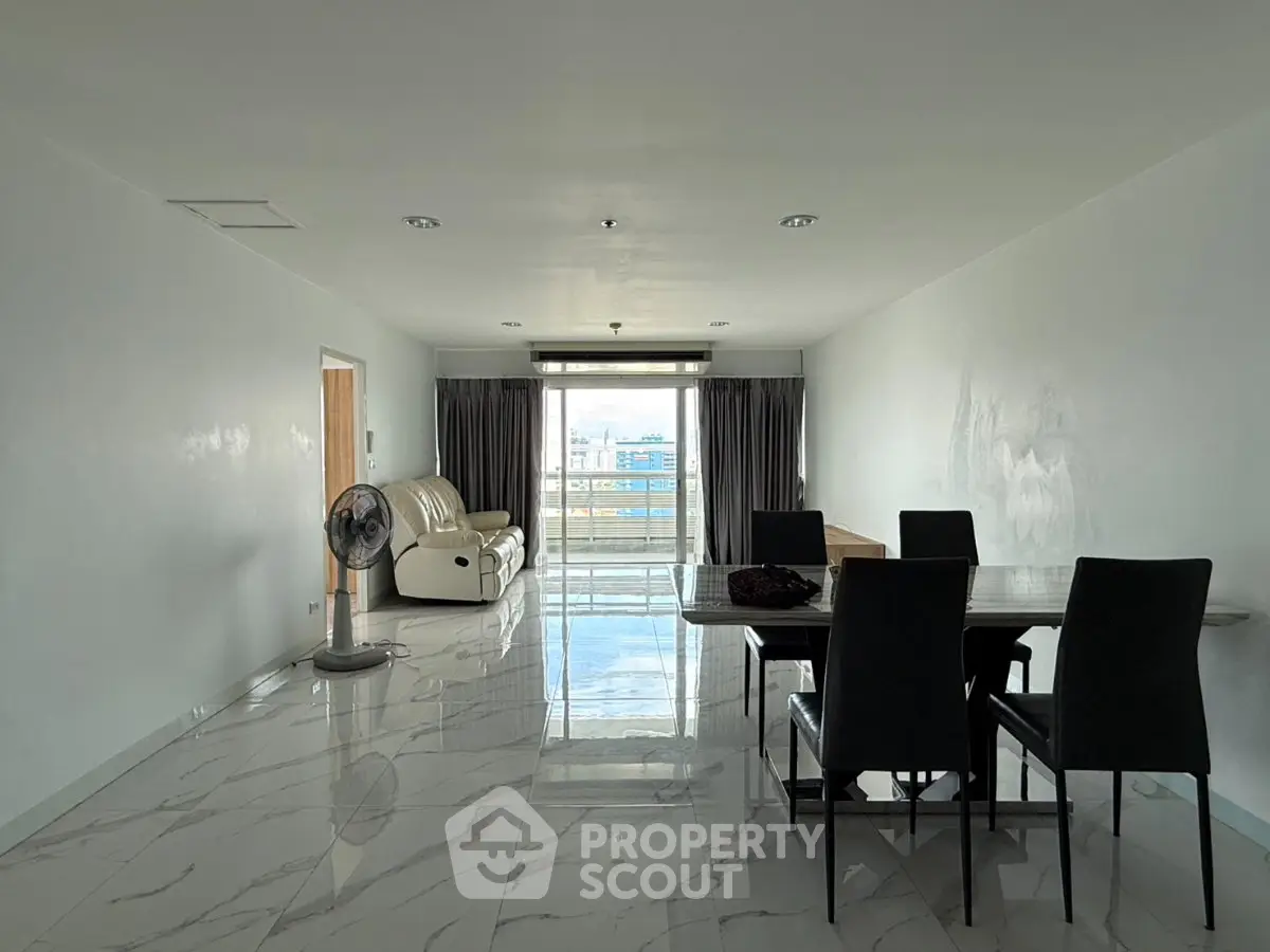 Spacious modern living room with elegant dining area and large windows offering city views.