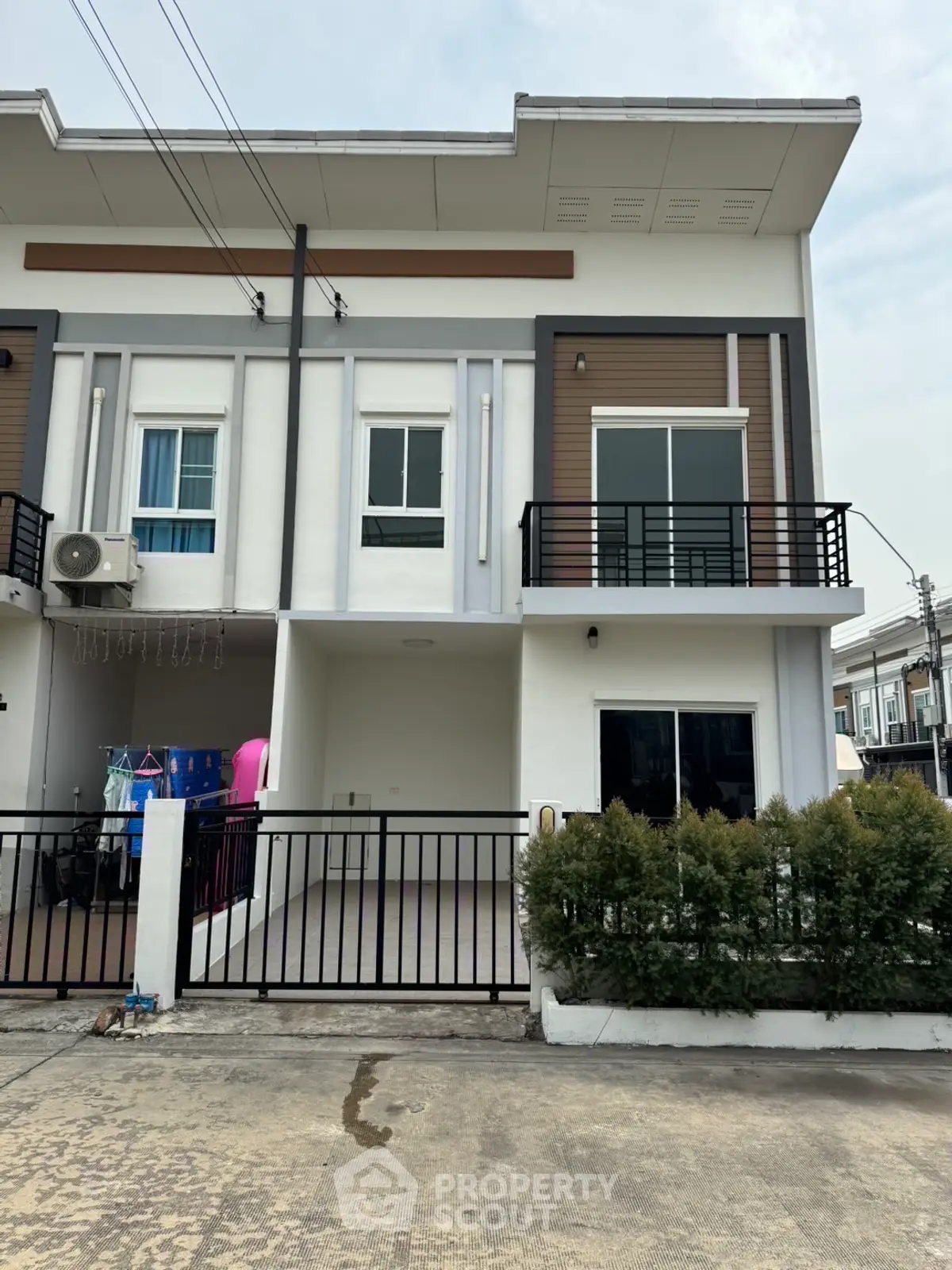 Modern townhouse exterior with balcony and gated entrance in urban setting