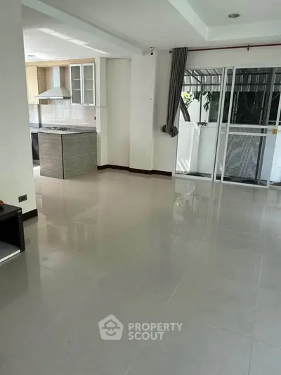 Spacious open-plan living area with modern kitchen and sliding glass doors to balcony.