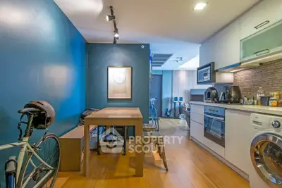 Modern kitchen with open layout and wooden flooring, featuring a dining area and bicycle storage.