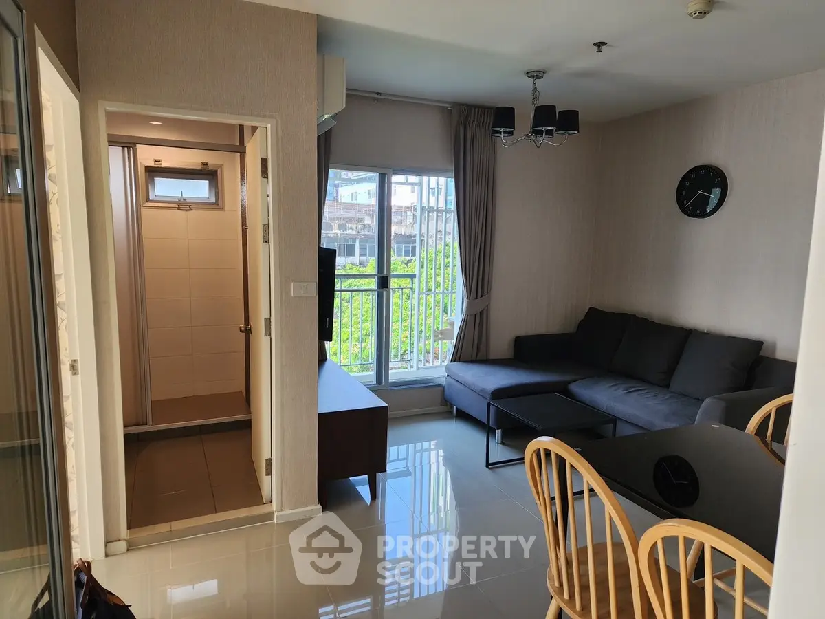 Modern living room with sleek furniture and natural light, adjacent to a compact bathroom.