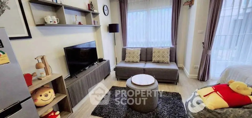 Cozy living room with modern decor and natural light, featuring a comfortable sofa and stylish shelving.