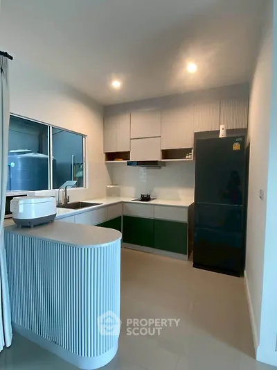 Modern kitchen with sleek cabinetry and black fridge in a stylish apartment.