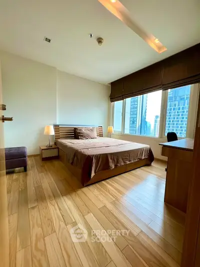 Spacious bedroom with wooden flooring and city view in modern apartment