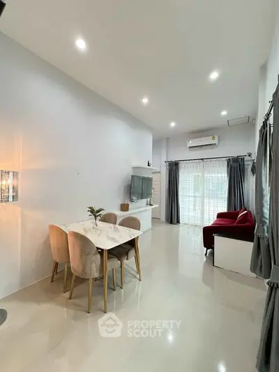 Modern living room with dining area, featuring sleek furniture and ample natural light.