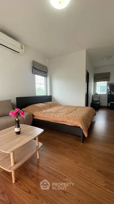 Cozy bedroom with wooden flooring and modern furnishings in a stylish apartment.
