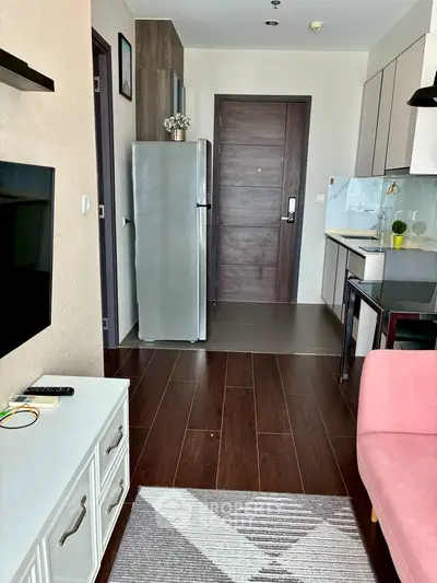 Modern apartment interior with sleek kitchen and cozy living area, featuring stylish decor and wooden flooring.