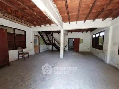 Spacious open-plan interior with wooden ceiling and tiled floor, ideal for renovation.