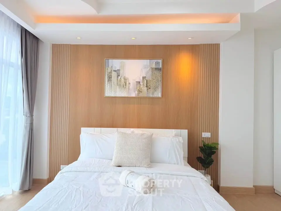 Modern bedroom with elegant decor and natural light, featuring a stylish wooden accent wall and cozy bedding.