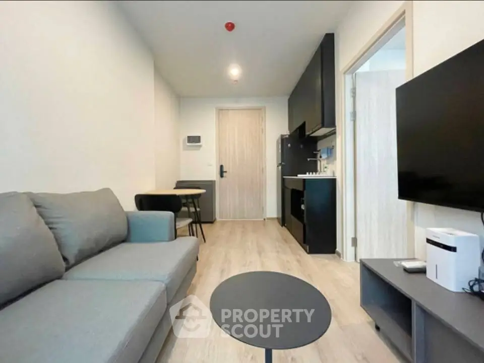 Modern living room with sleek furniture and open kitchen layout in a stylish apartment.