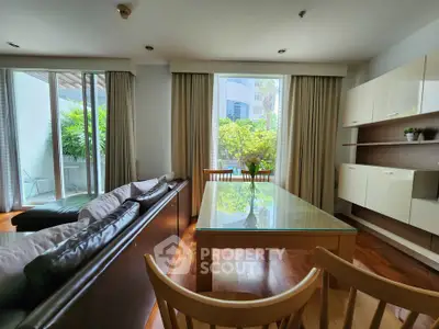 Spacious living room with modern furniture and large windows overlooking greenery.