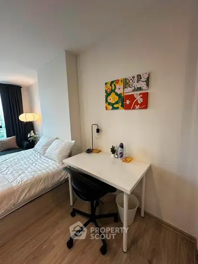 Modern bedroom with study area, featuring a cozy bed, sleek desk, and vibrant wall art, perfect for urban living.