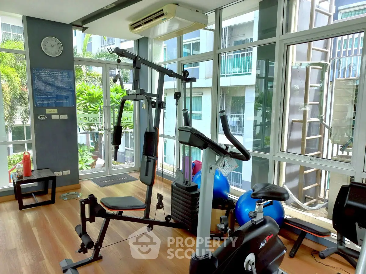 Modern gym with exercise equipment and large windows in a residential building.