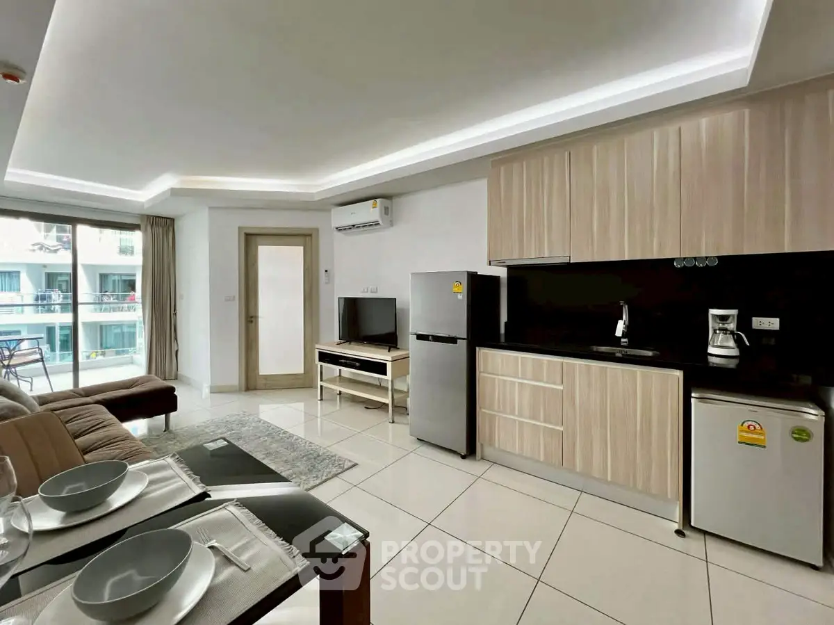 Modern open-plan living room with sleek kitchen and balcony view in a stylish apartment.
