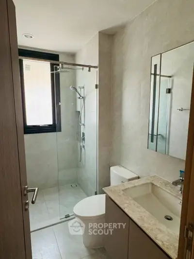 Modern bathroom with glass shower and sleek fixtures in a contemporary apartment.