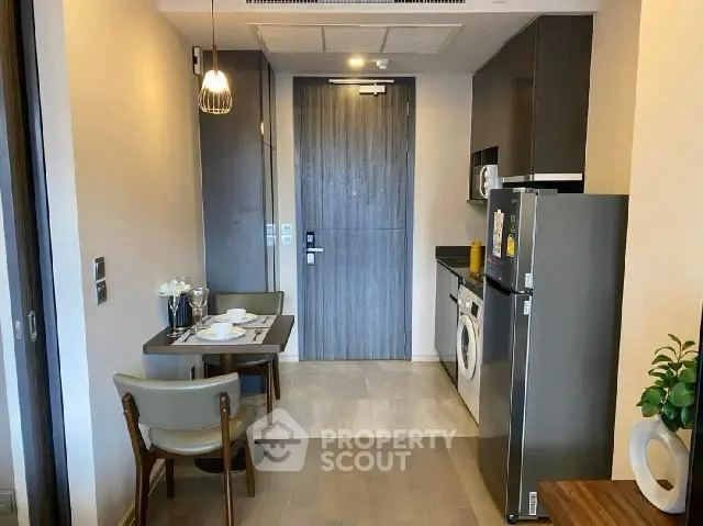 Modern apartment interior with compact kitchen and dining area, featuring sleek appliances and stylish decor.