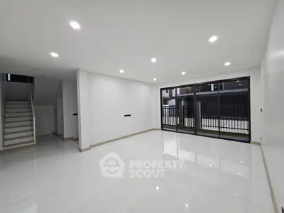 Spacious modern living room with large windows and sleek tile flooring.