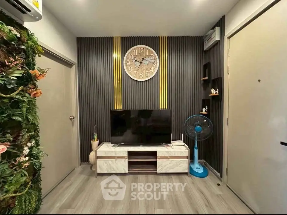 Modern living room with stylish decor and wall clock, featuring a TV and air conditioning.