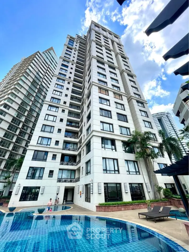 Luxurious high-rise building with poolside view and modern architecture.