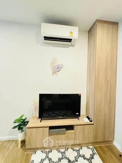 Modern living room with sleek TV unit and air conditioning, featuring minimalist decor and wooden flooring.