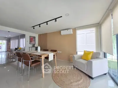 Spacious modern living room with dining area, featuring sleek furniture and abundant natural light.