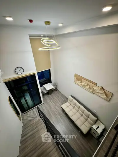 Modern loft-style living room with high ceiling and contemporary lighting