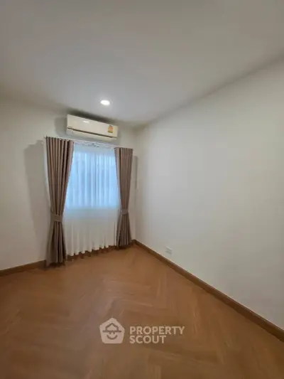 Spacious empty room with wooden flooring and air conditioning, perfect for customization.