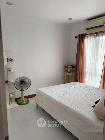 Cozy bedroom with natural light, featuring a fan and air conditioning for comfort.