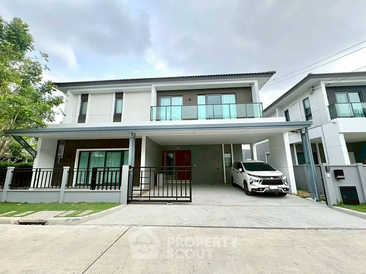 Modern two-story house with spacious driveway and sleek balcony design.