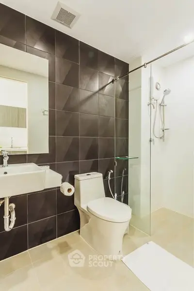 Modern bathroom with sleek design, featuring glass shower and stylish tiles.