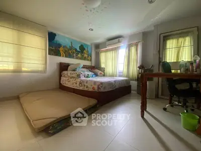 Spacious bedroom with natural light, featuring a cozy bed and a work desk, ideal for comfort and productivity.