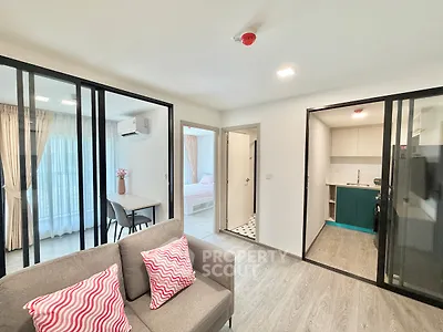 Modern open-plan living room with glass partitions, cozy seating, and stylish kitchen in a contemporary apartment.