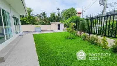 Spacious garden area with lush greenery and modern fencing in a serene residential setting.