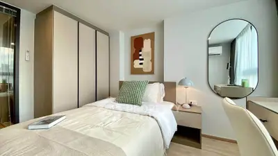 Modern bedroom with stylish decor and ample natural light, featuring a cozy bed and sleek furniture.