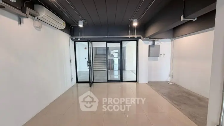 Spacious modern interior with glass doors and tiled flooring, ideal for versatile use.