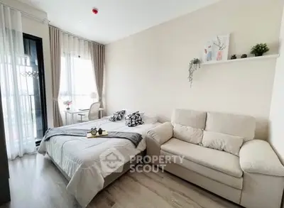 Cozy bedroom with modern decor and natural light, featuring a comfortable bed and stylish sofa.