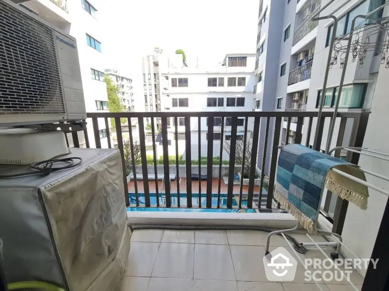 Charming balcony view overlooking modern apartment complex with pool, perfect for relaxation and leisure.