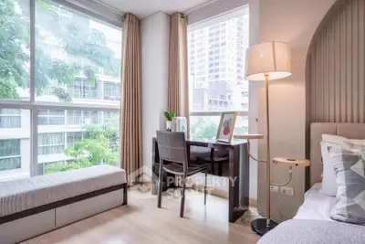 Bright modern bedroom with large windows and stylish decor in urban setting.